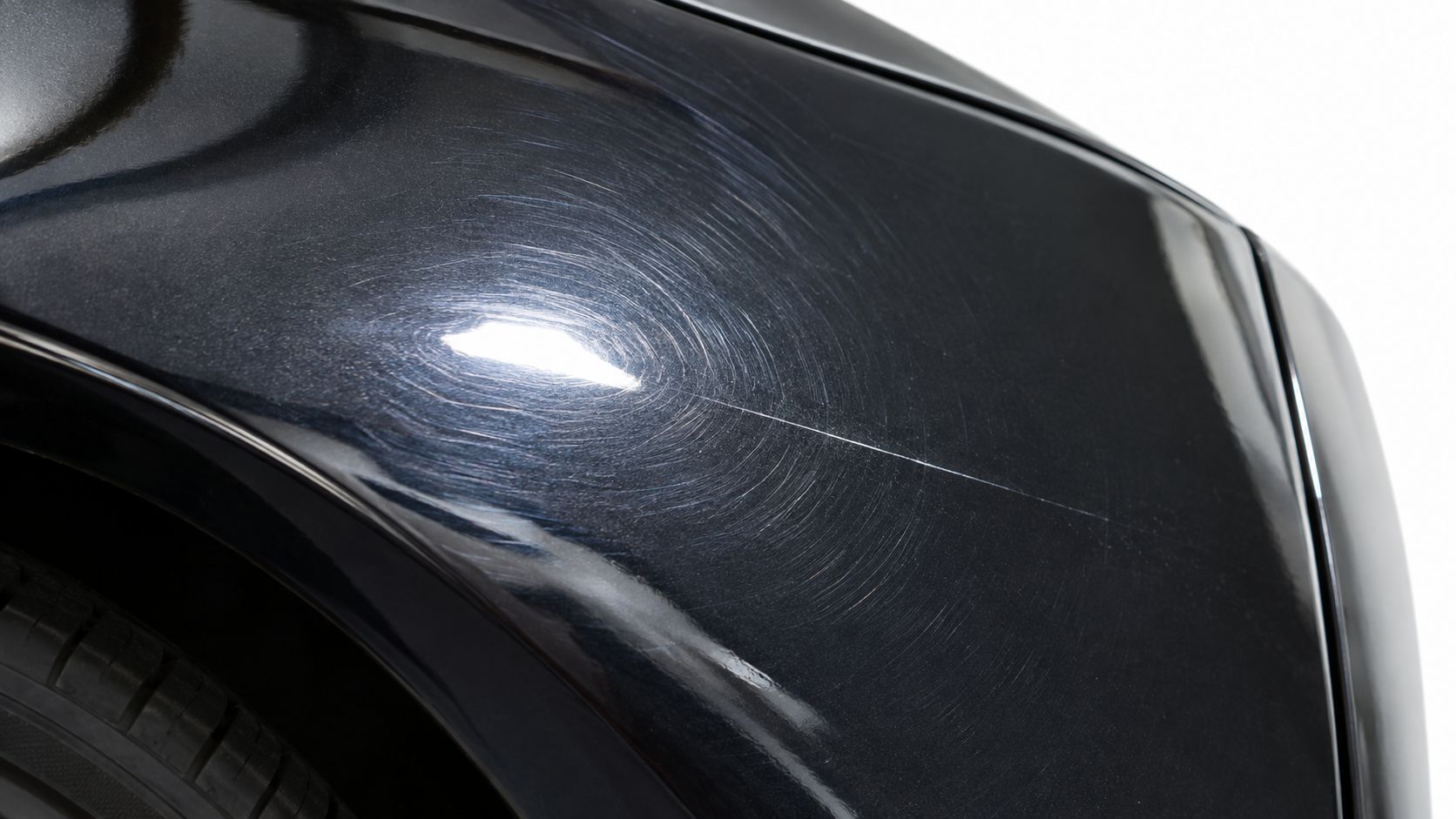 A close-up view of a car panel showing visible swirl marks and a deep scratch in the paint.