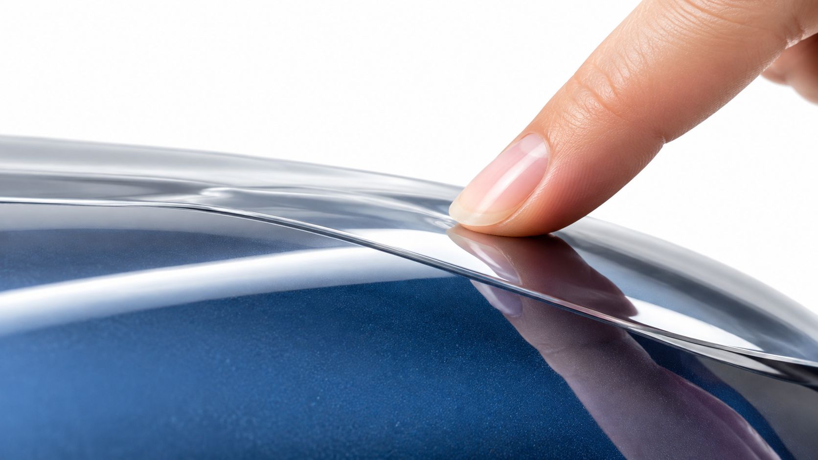 A close up of a human finger touching the smooth glossy surface of a blue car